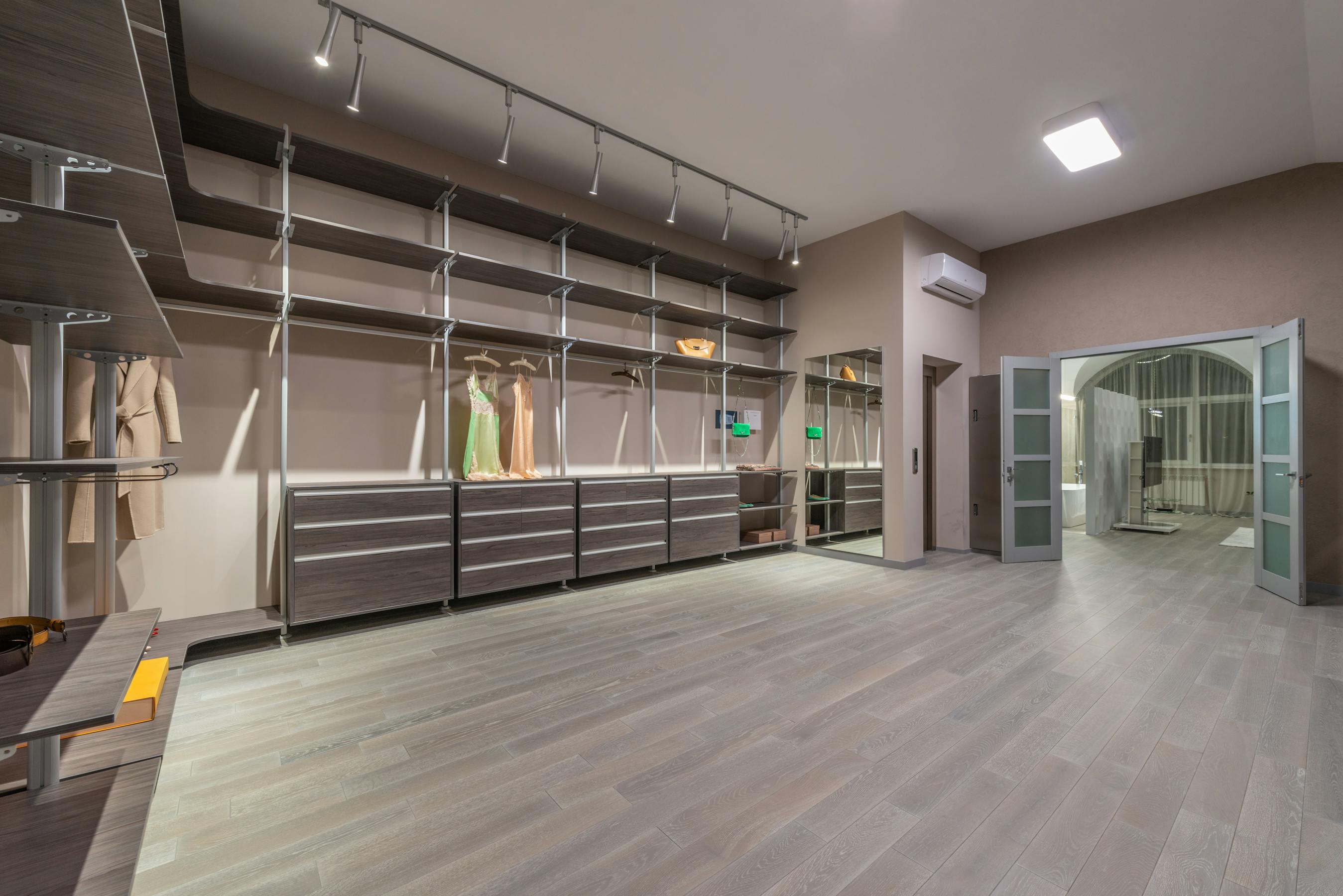 Bespoke walk-in closet with walnut shelving, brass rods, and warm LED lighting
